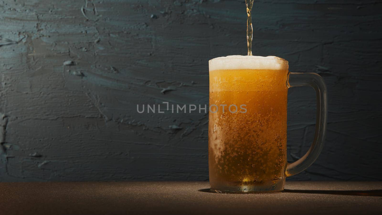 Cold beer in mug on the table with rough background