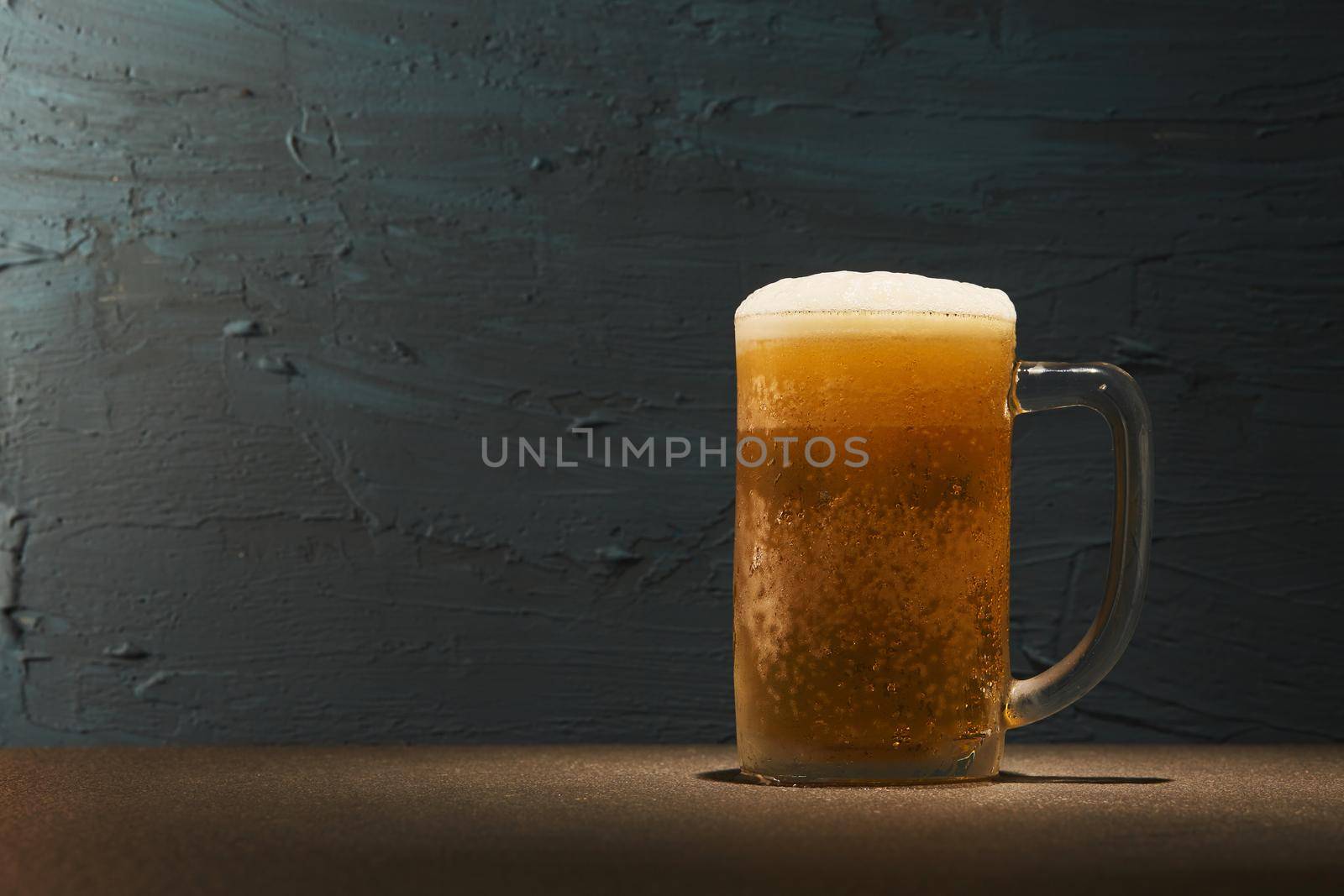 Cold beer in mug on table with rough background