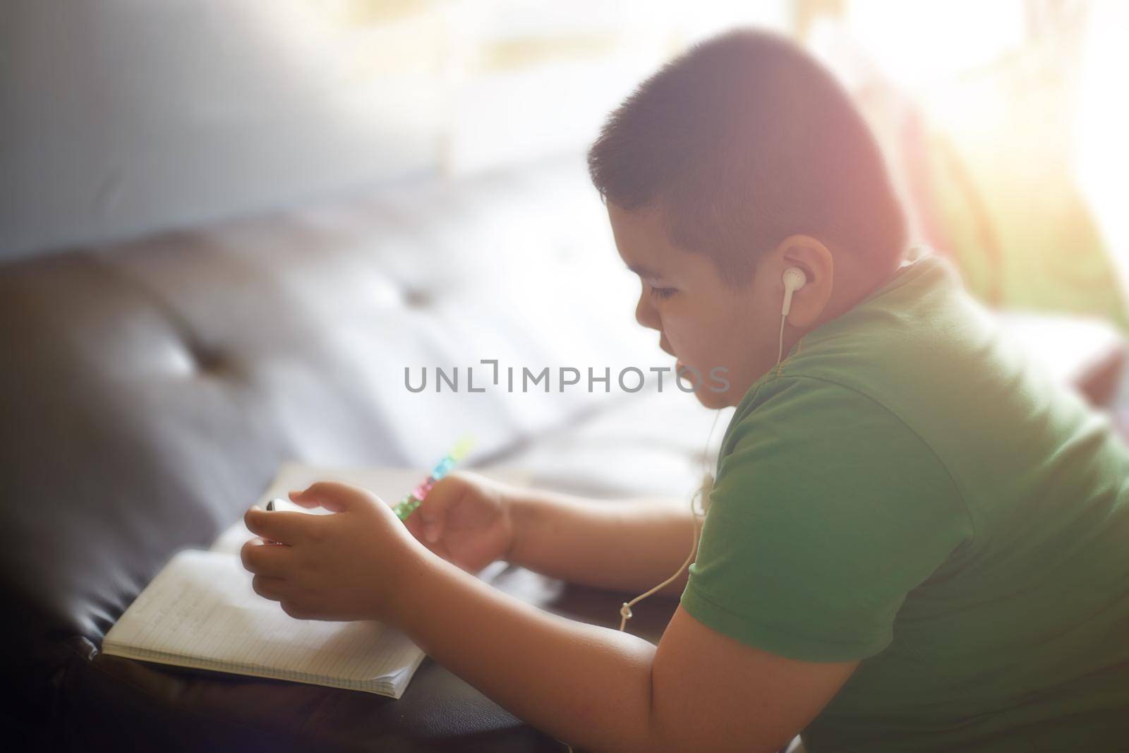 e-Learning at home, Smart looking Asian preteen boy, thinking and looking at smartphone at home