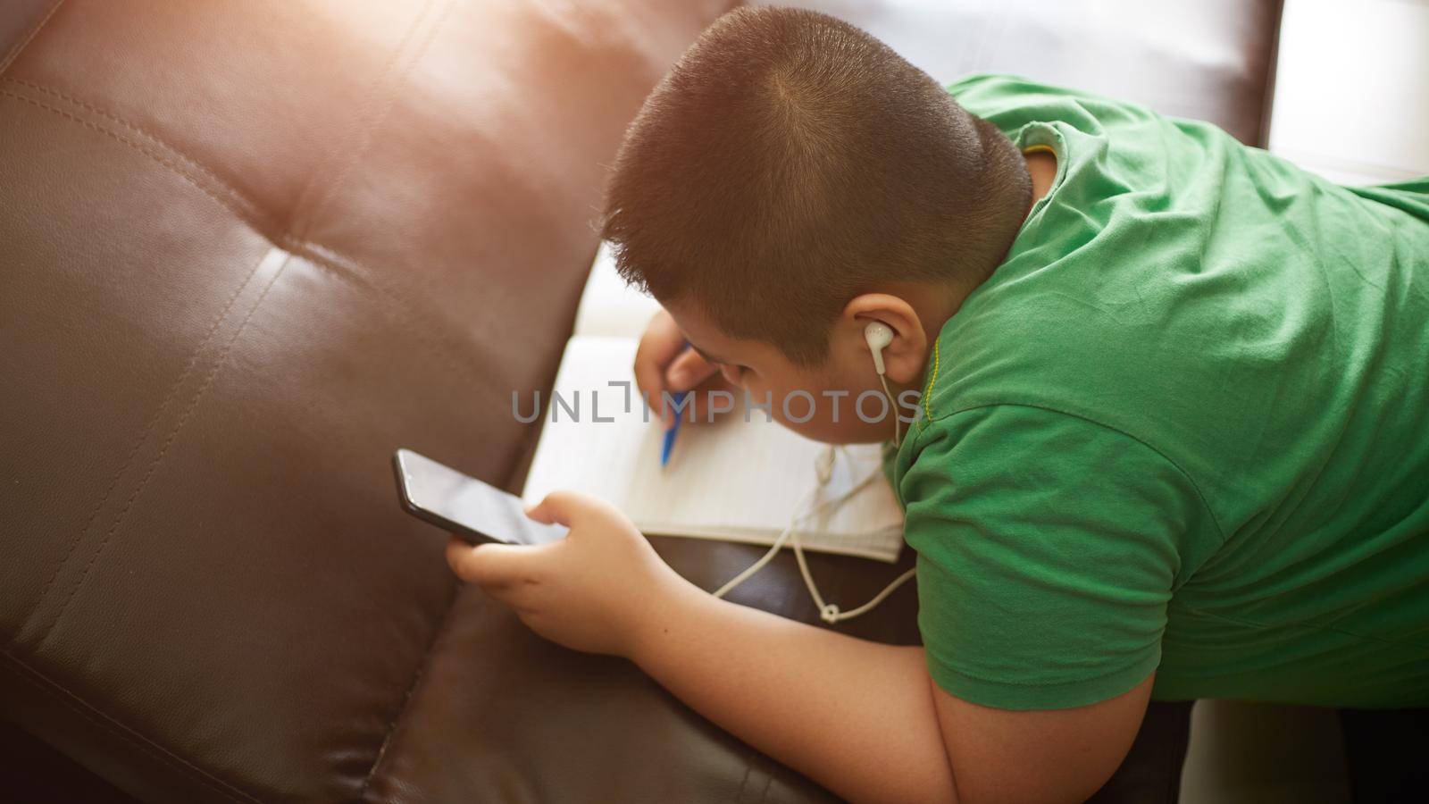 e-Learning at home, Smart looking Asian preteen boy, thinking and looking at smartphone at home