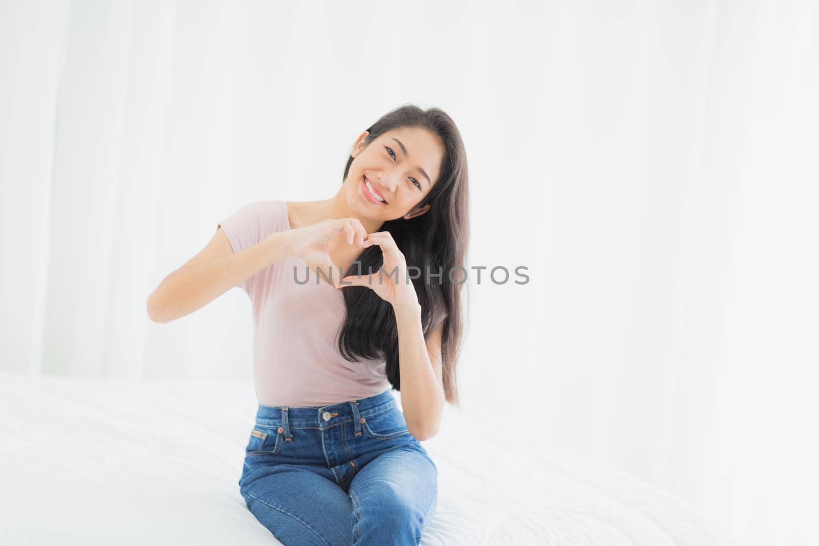 Beautiful Asia woman is smiling with love sign to hands