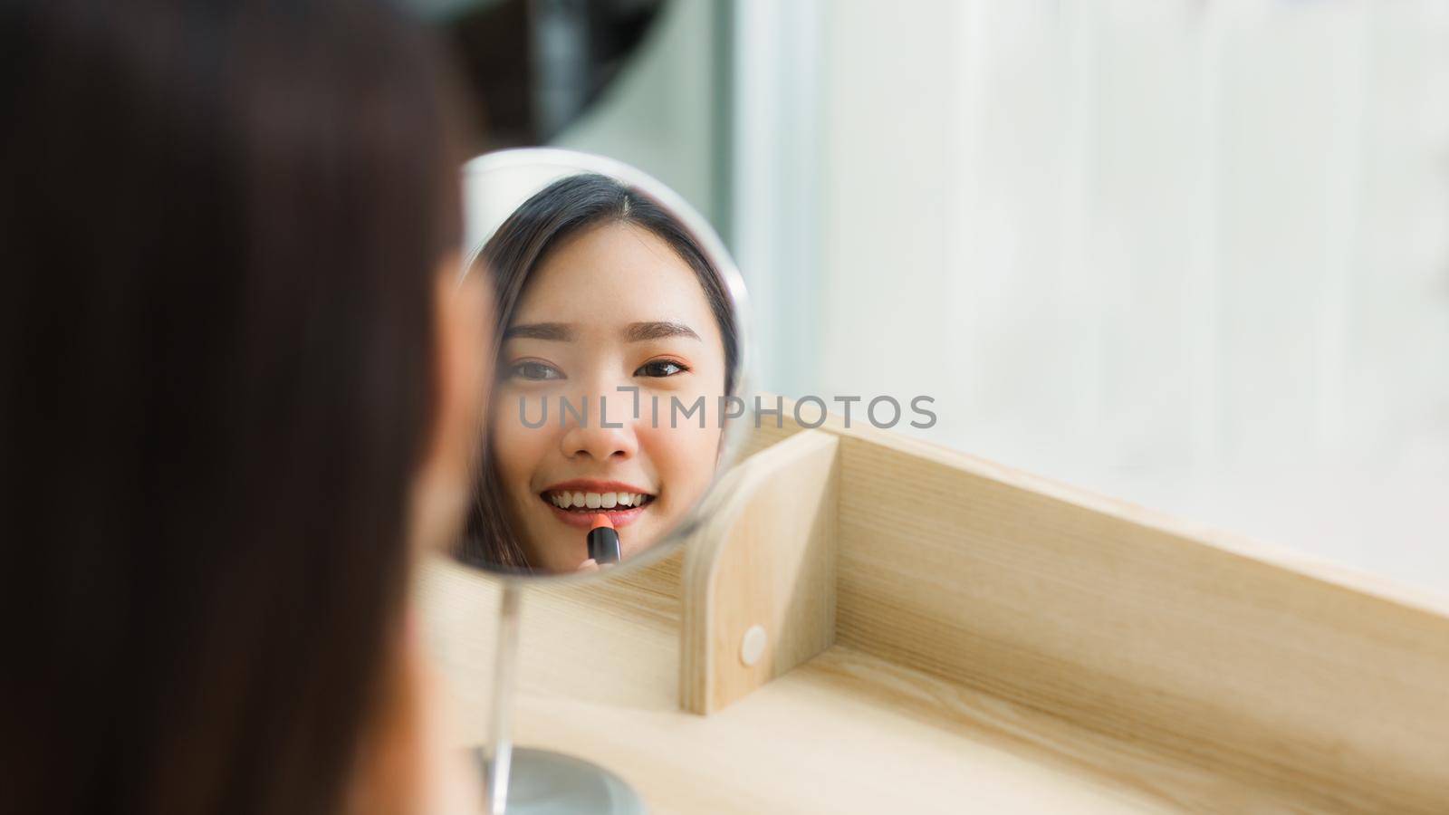 Young women make up lipstick on the mirror