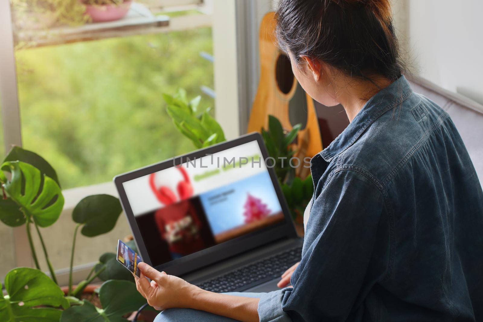 Woman is holding credit card and using laptop computer. Online shopping and work from home concept.
