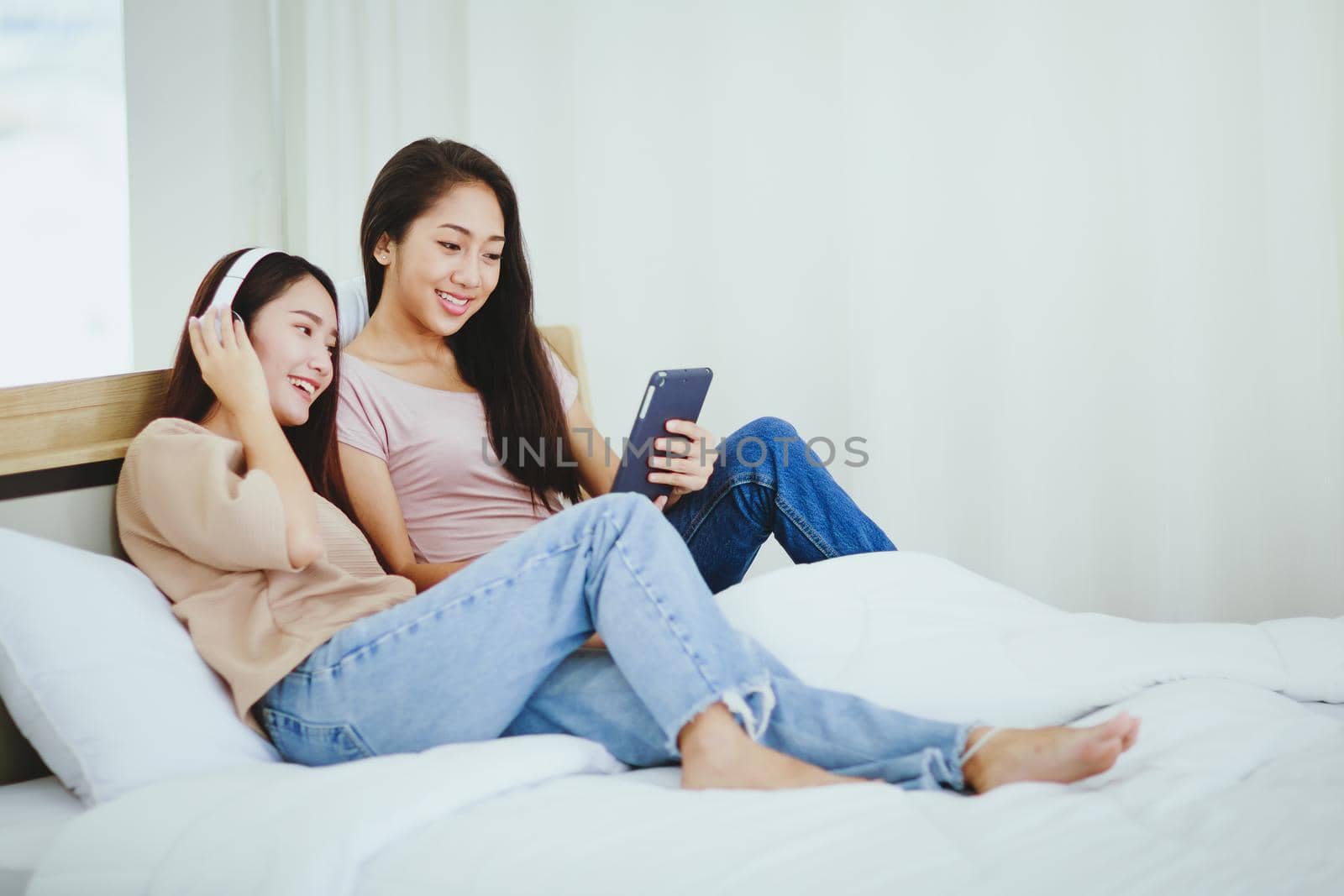 Couple women relaxing on bed using digital tablet for video call