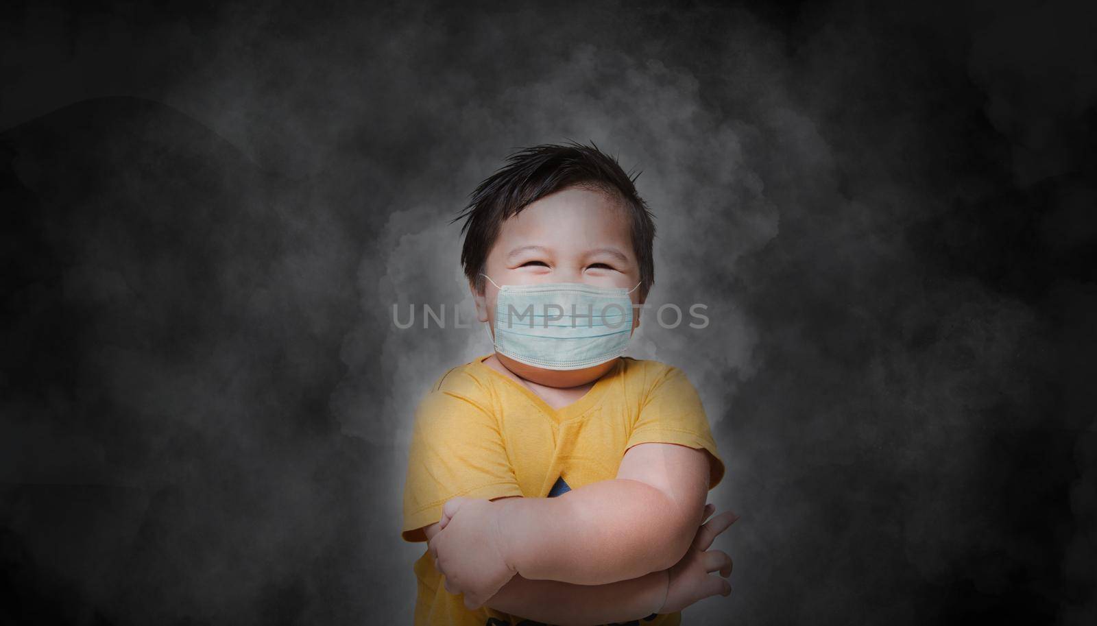 Little boy in a disposable mask with dust and smoke background. Asian kid is wearing the mask for protect them self from virus and air pollution.