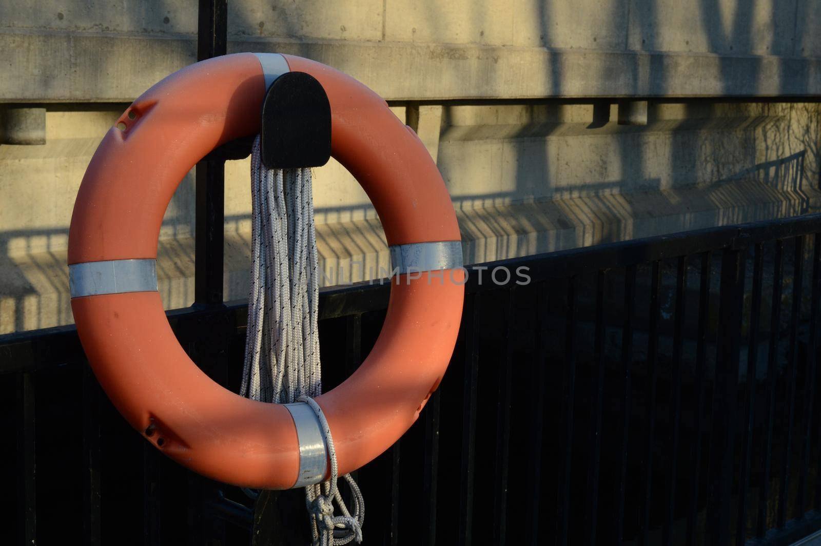 A bright orange life preserver is attached to the side of a water Dam bridge located at Old Slys Locks in small town Smiths Falls, Ontario.