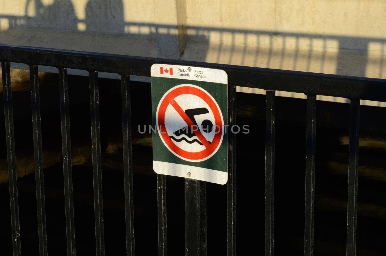 SMITHS FALLS, ONTARIO, CANADA, MARCH 22, 2021: A no swimming sign is posted at the Old Slys Locks water Dam on the Rideau Canal in small town Smiths Falls.