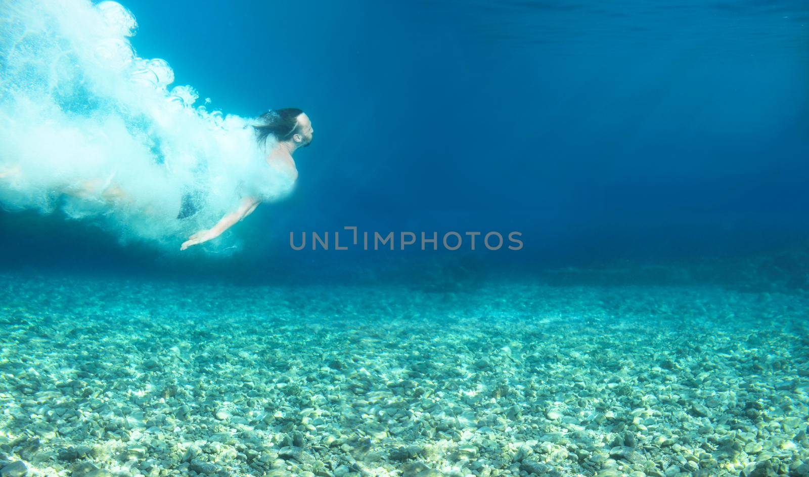 Man swimming under water in blue transparent sea underwater shot copy space for text