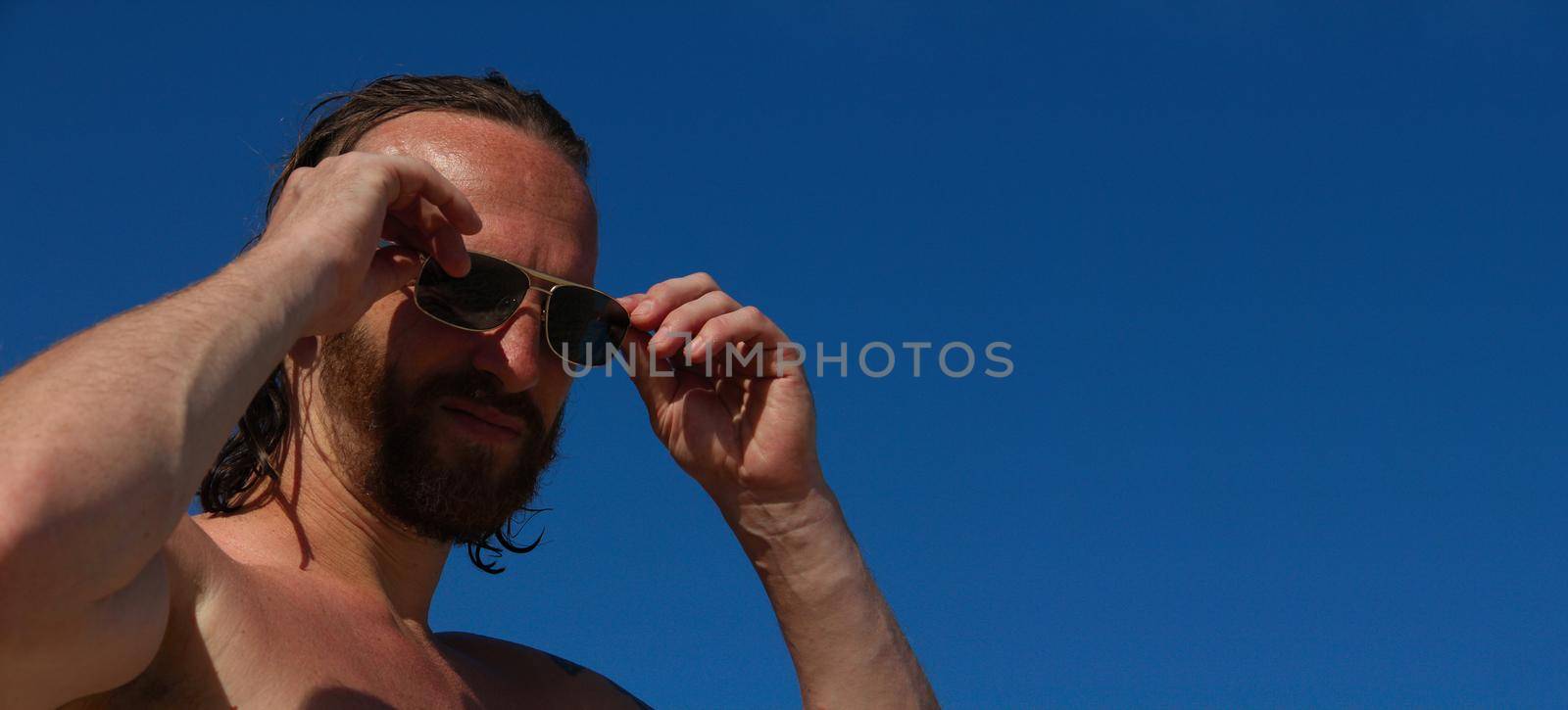 Close up portrait of mid adult man in sunglasses with wet hair on the beach seaside vacation male skincare concept