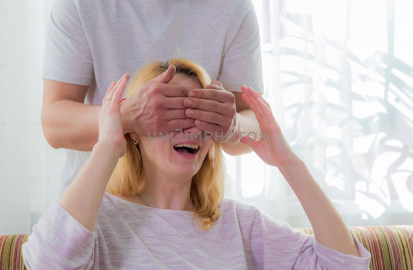 The family makes a surprise for mom, wishes her a happy holiday. Dad covered his mother's eyes with his palms.