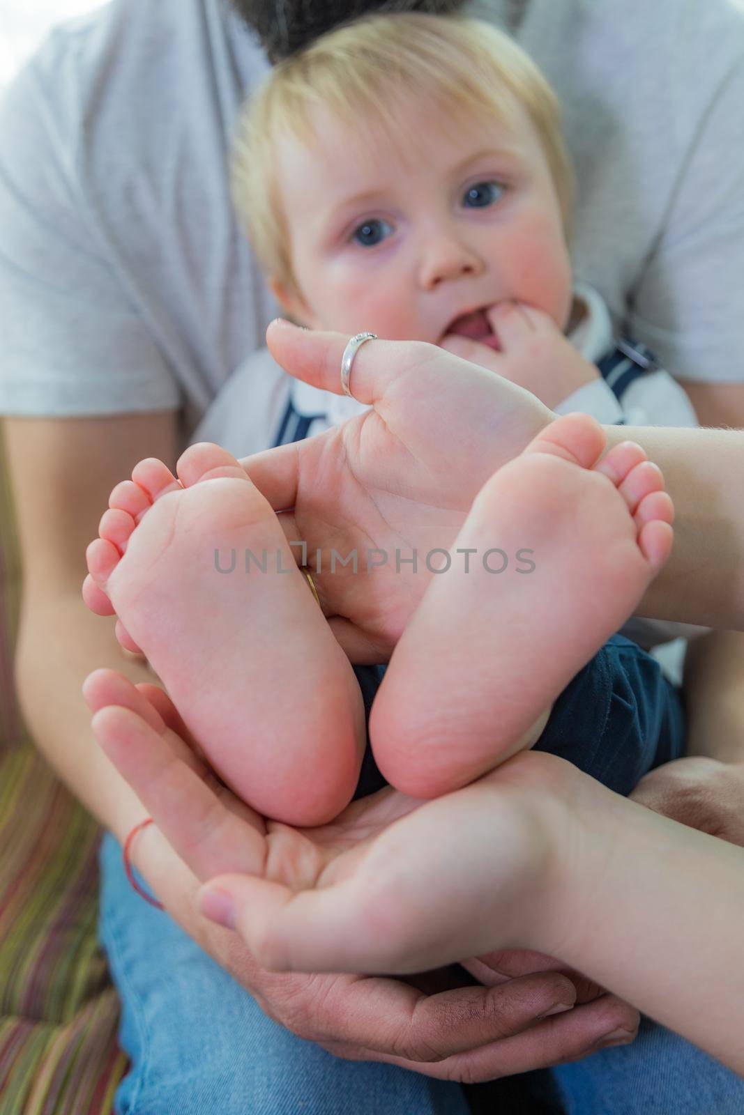 Parents and children hold the baby's heels in the palms of their hands. by Yurich32