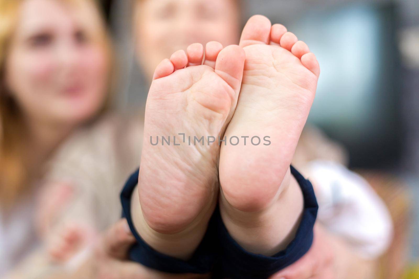 Parents and children hold the baby's heels in the palms of their hands. by Yurich32