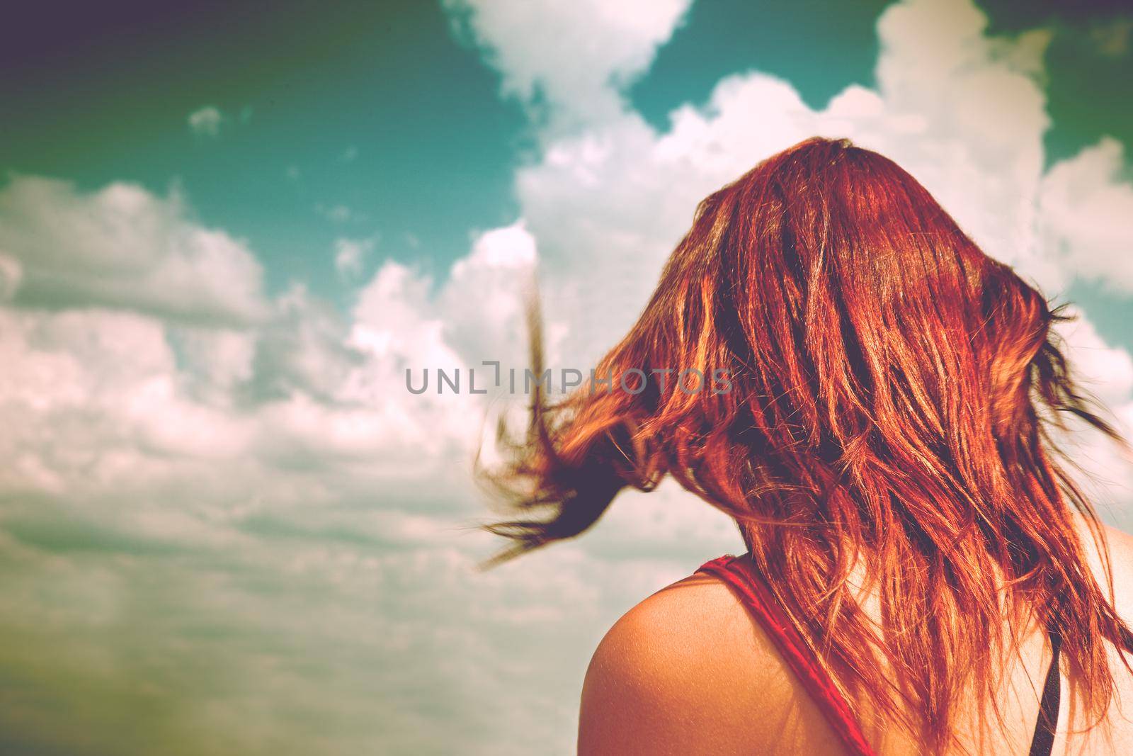 anonymous woman with red hair and blue sky