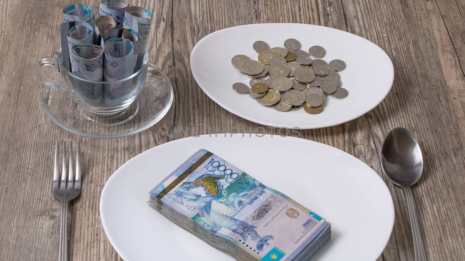 Kazakhstani tenge on a plate and a mug on the table. The national currency of Kazakhstan. Salary in tenge. Grocery basket, saving the budget.