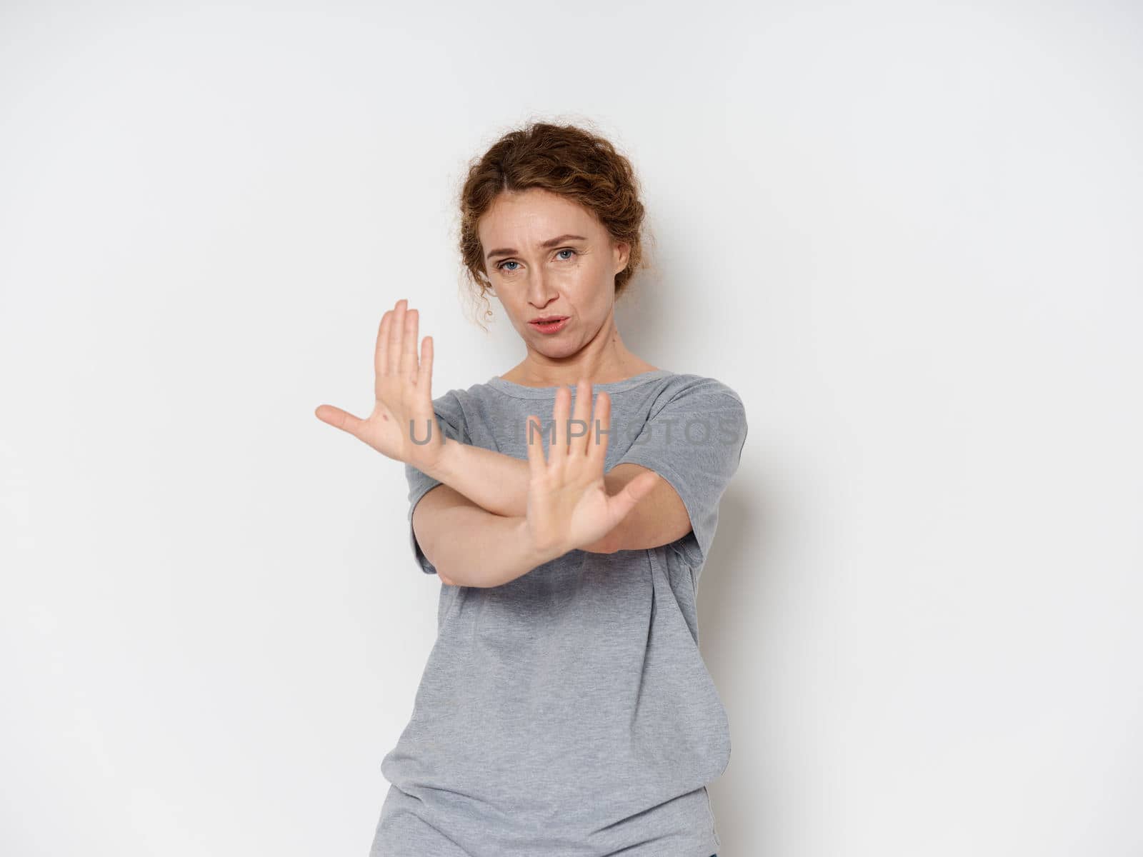 Elderly woman shows negative gesture with hands over isolated background