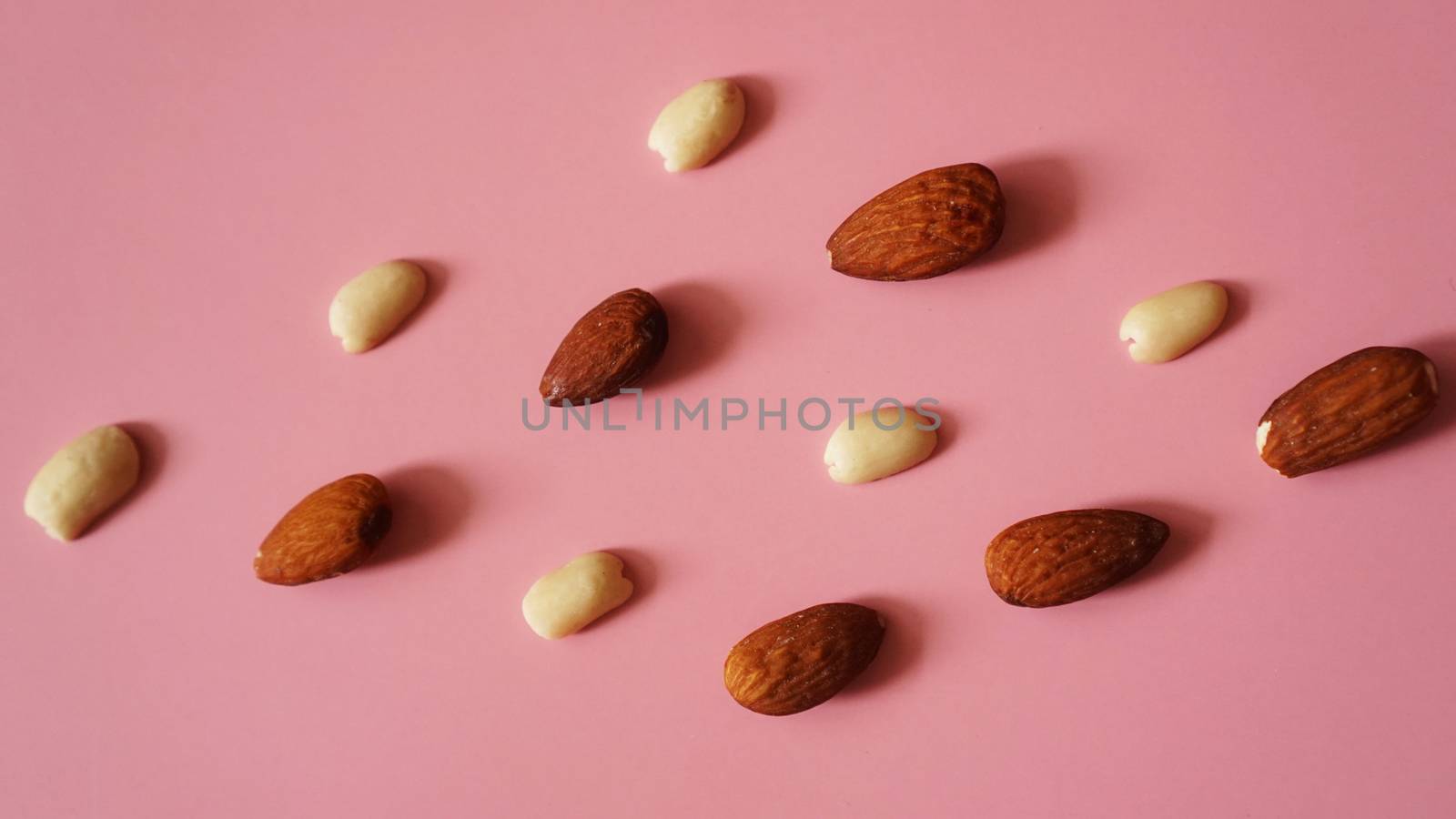 Almonds and peanuts on a pink background by natali_brill