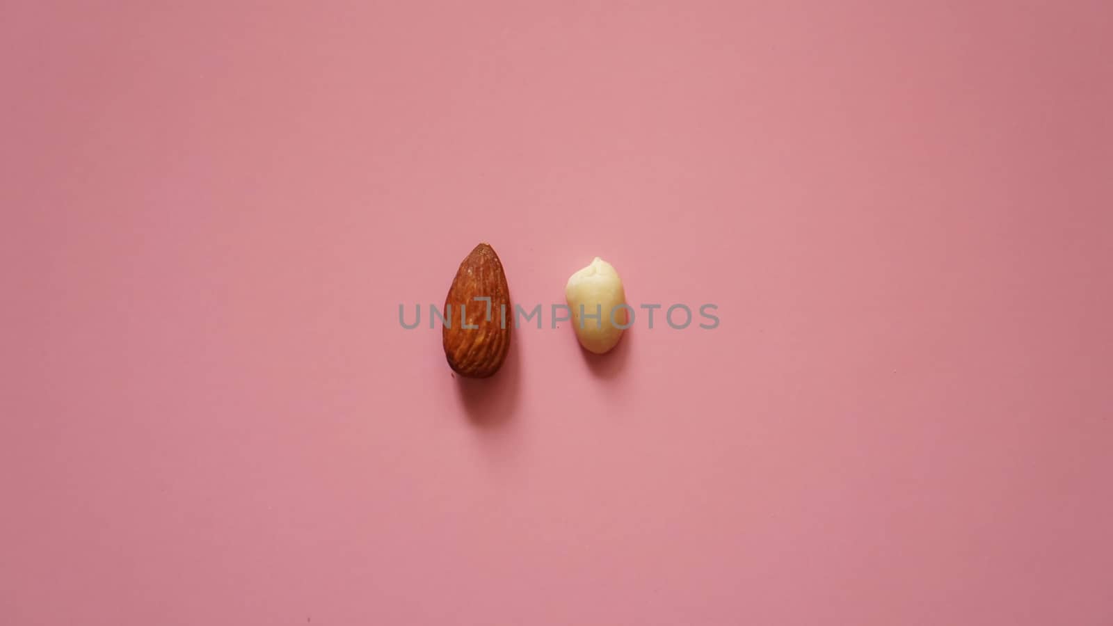 Almonds and peanuts on a pink background - bright summer picture