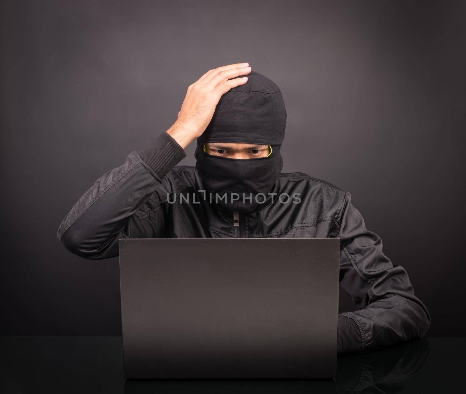 Computer hacker dizziness or headache - Male thief stealing data from laptop computer on black background