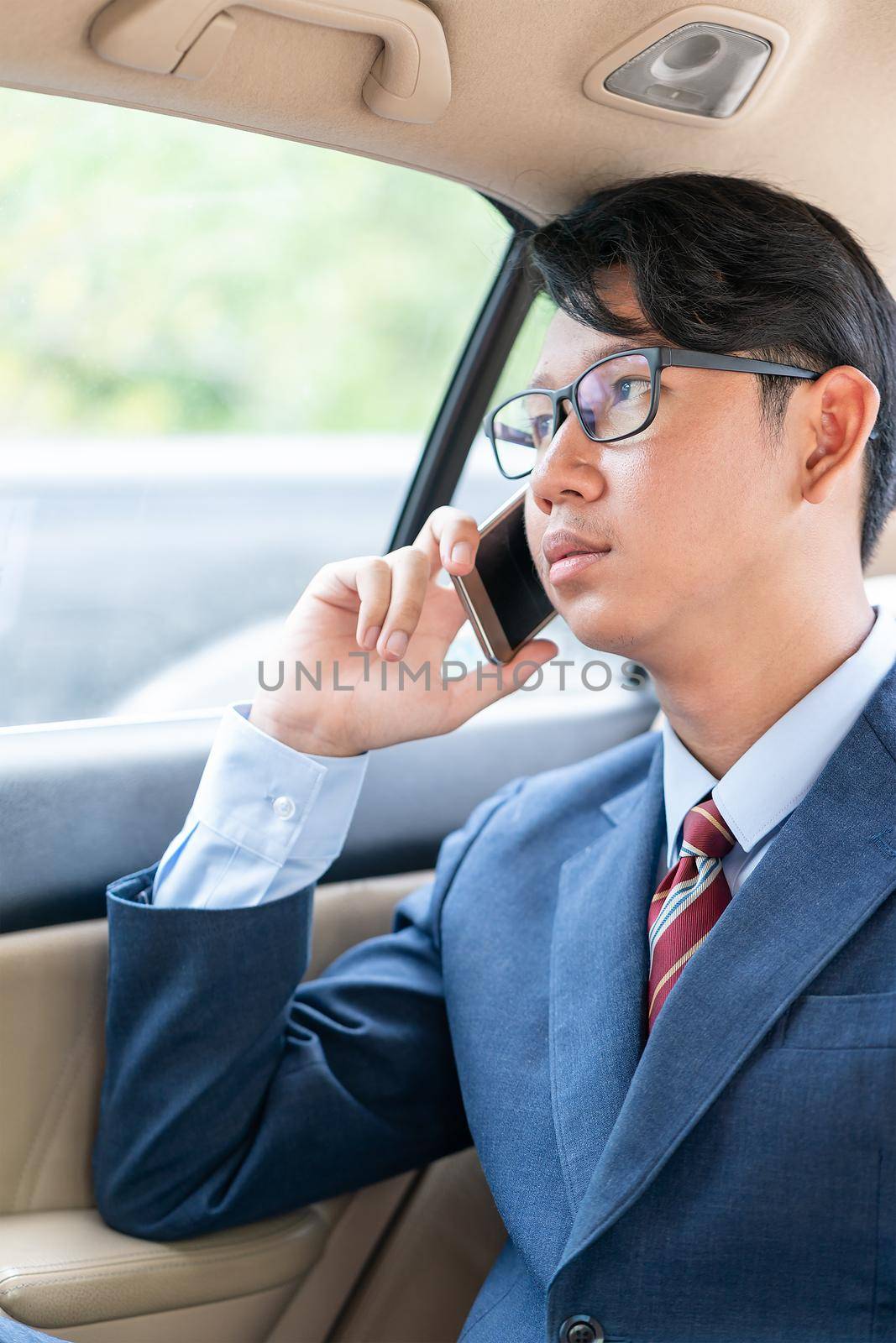 Young asian business men portrait in suit  talking on the phone in car