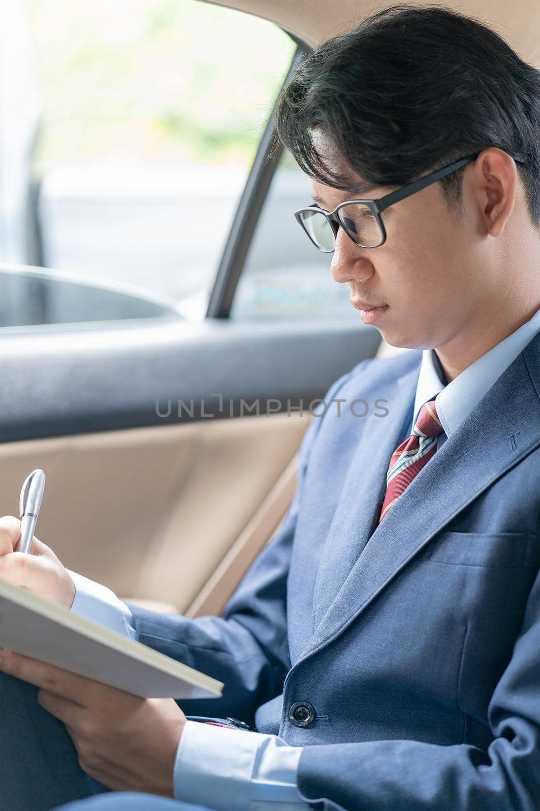 Young asian business men portrait in suit working in the backseat of a car