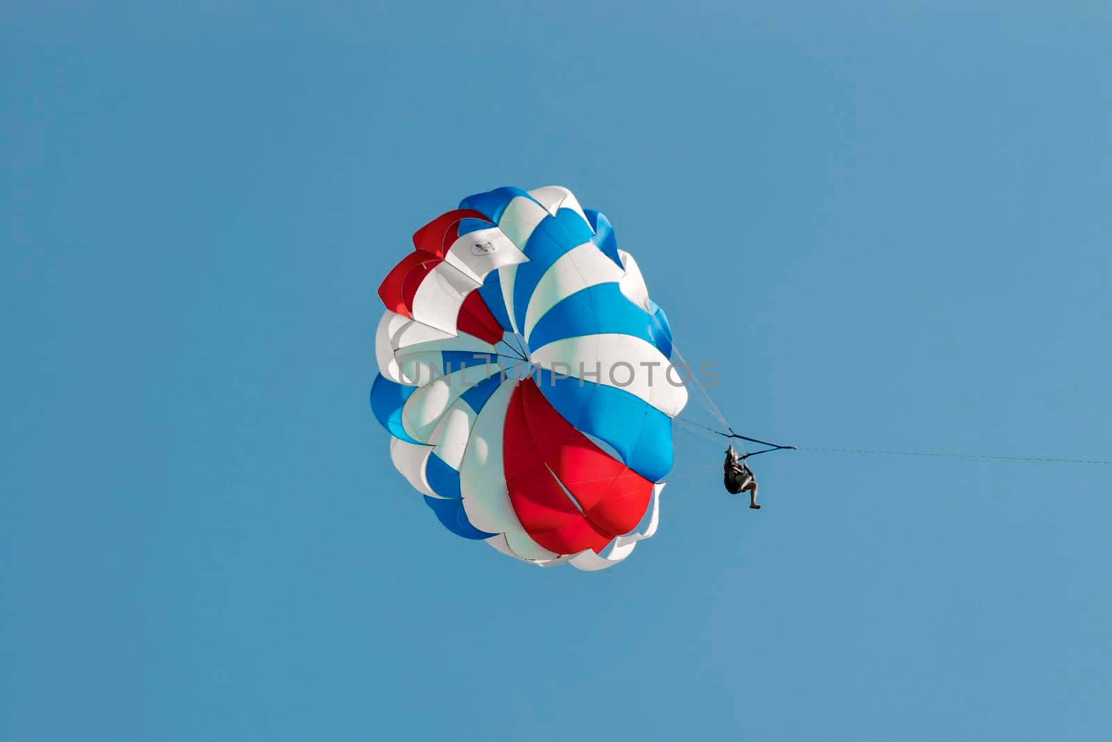 Parasailing people against a blue sky on black sea. Sunny summer day. Side view. Crimea, Sudak - 10 October 2020. by Essffes