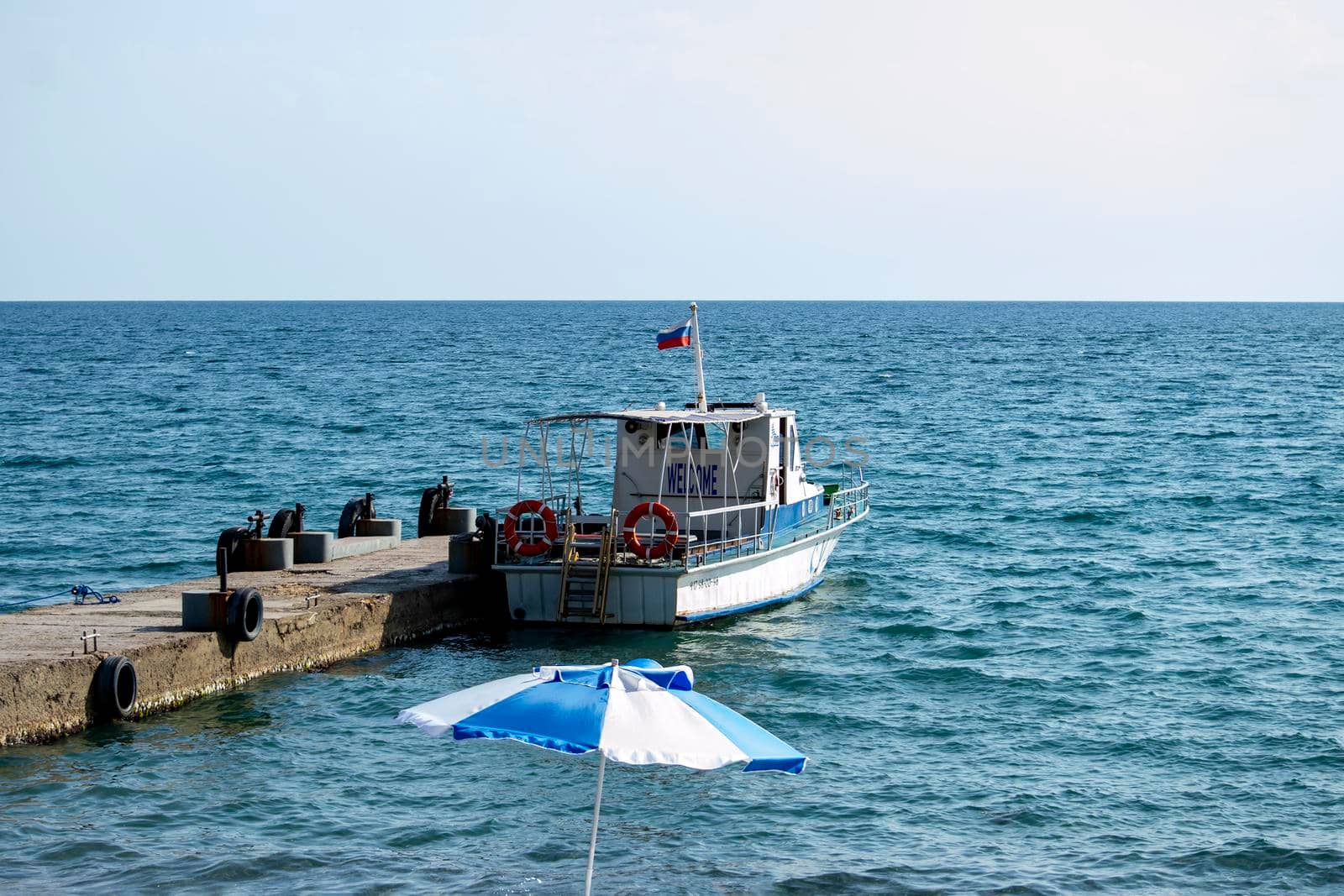 The sea boat moored to the pier. Sunny summer day. Back view. Crimea, Sudak - 10 October 2020. by Essffes