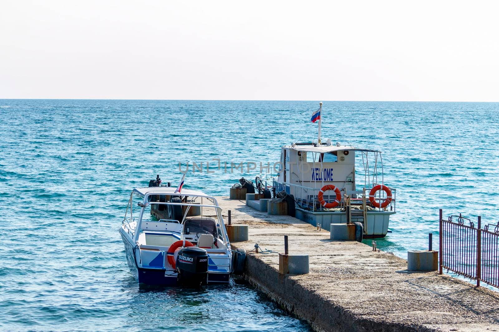 The sea boats moored to the pier. Sunny summer day. Front view. Crimea, Sudak - 10 October 2020. by Essffes
