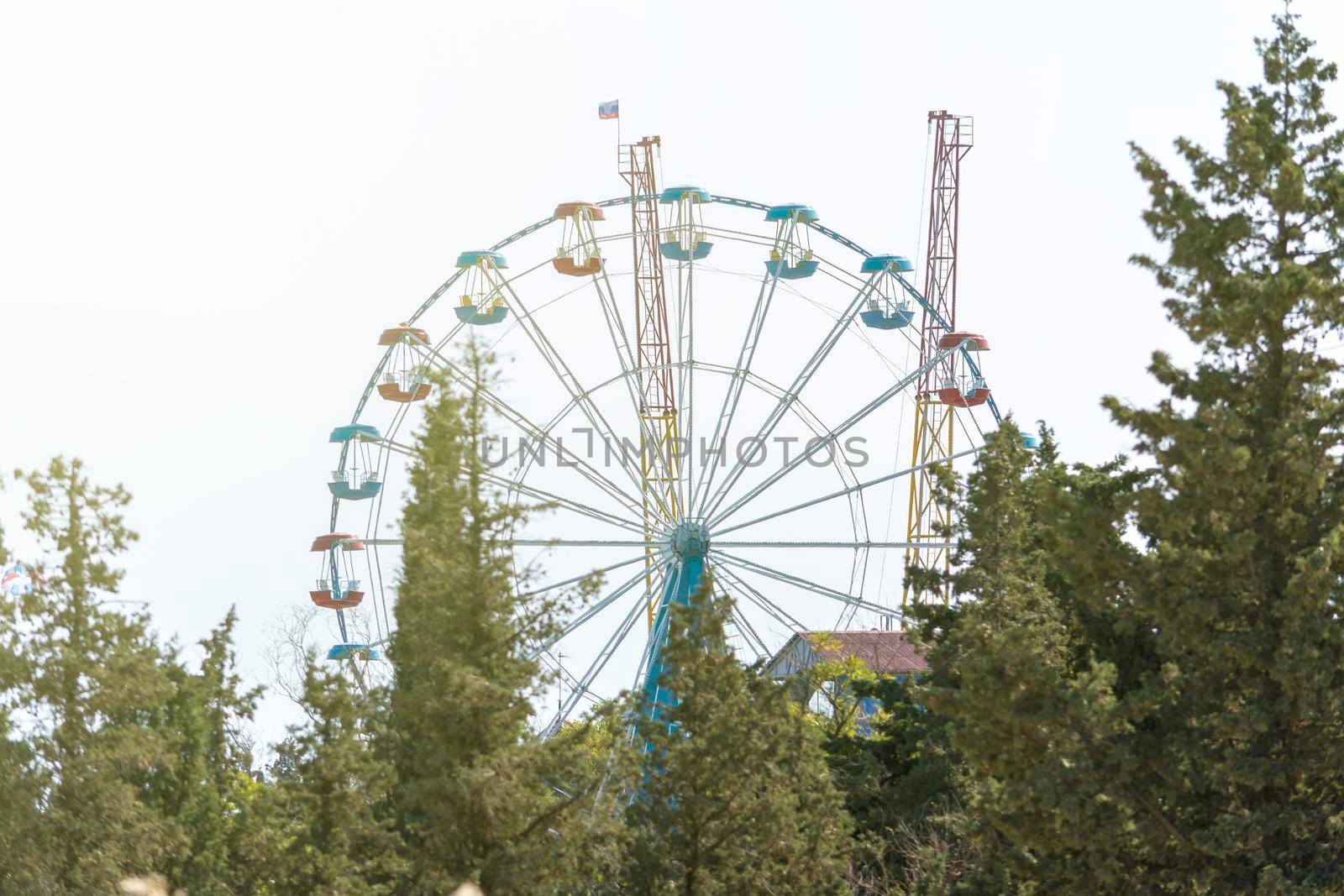 Ferris wheel and other attractions. Sunny summer day. Front view. Crimea, Sudak - 10 October 2020. by Essffes