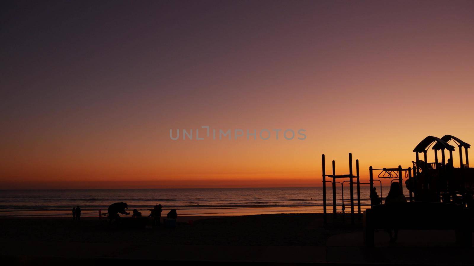 Oceanside, California USA - 8 Feb 2020: Silhouette of people making bbq campfire. Beachfront recreation area for barbeque with fire place on pacific ocean coast. Bonfire for barbecue on sunset beach.