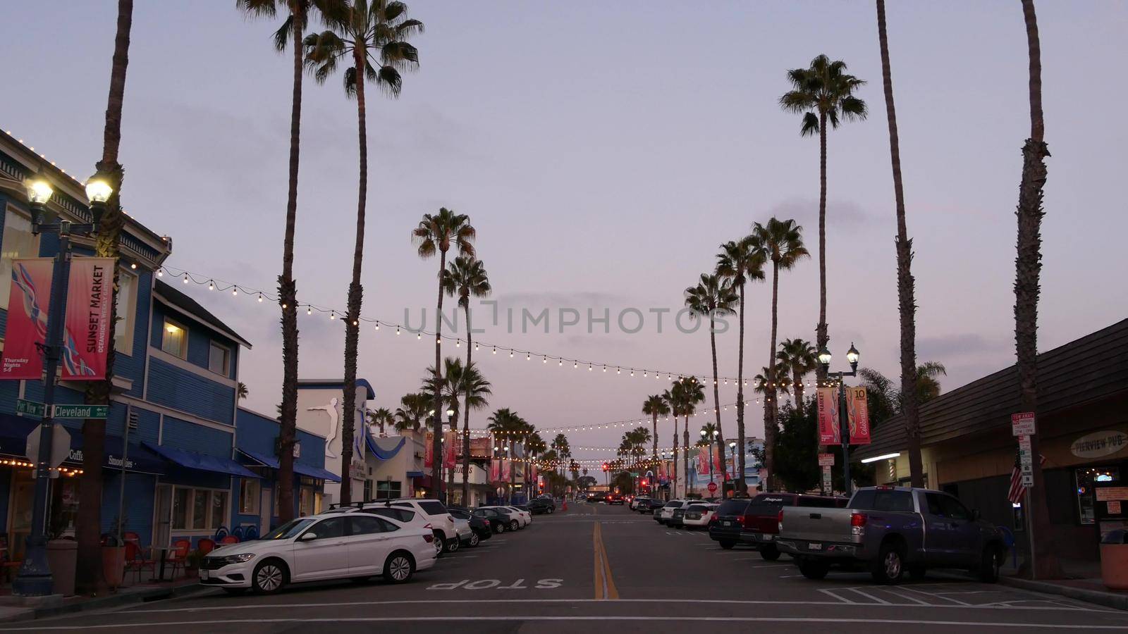 Oceanside, California USA - 18 Feb 2020: Pier View Coffee cafe. Palm trees in twilight, typical american street, pacific coast tropical beach resort. Cars parked on road, generic view of evening city.