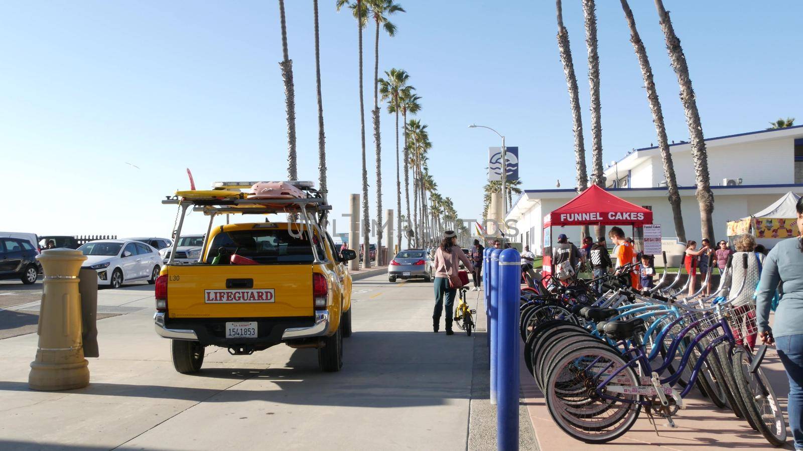 People walking, waterfront promenade, beachfront lifeguard. Ocean beach near Los Angeles, California by DogoraSun