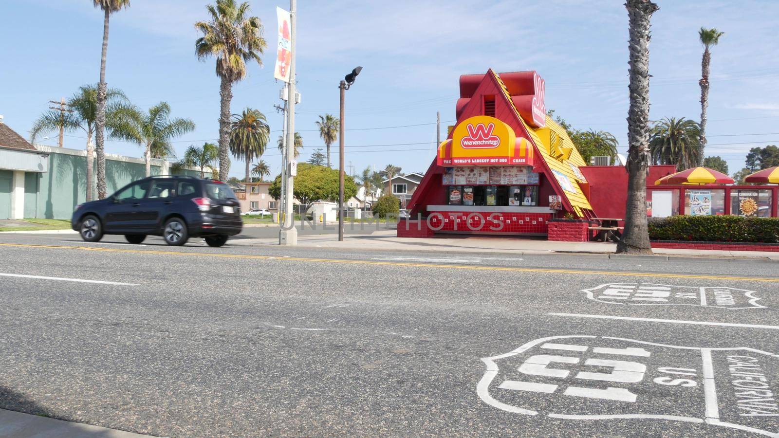 Oceanside, California USA - 20 Feb 2020: Wienerschnitzel hot dog fast food on pacific coast highway 1, historic route 101. Palm trees on street, road along ocean. Road trip vacations in united states.