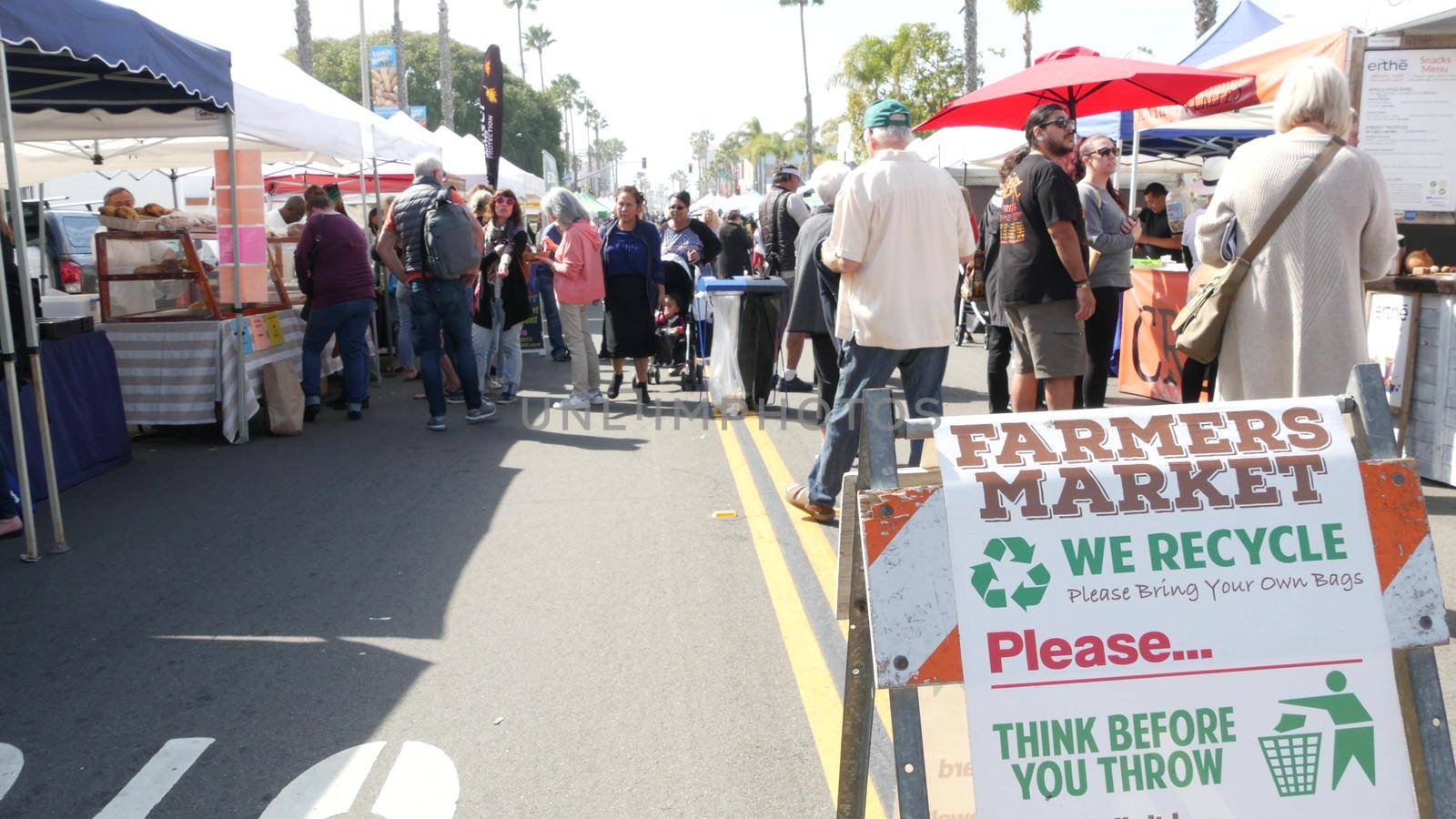 Oceanside, California USA -20 Feb 2020 People walking on marketplace, customer on farmers market. Vendors sell to byers locally produced goods. Street trading stalls and tents. We recycle plastic free