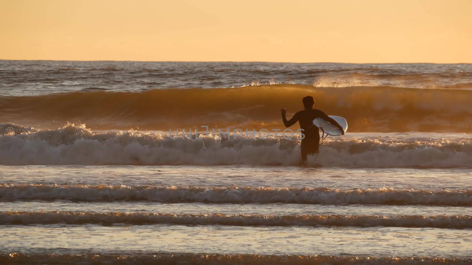 Oceanside, California USA - 27 Dec 2019: Surfer silhouette, pacific ocean beach in evening, water waves and sunset. Tropical coastline, waterfront vacation resort. People enjoy surfing as sport hobby.