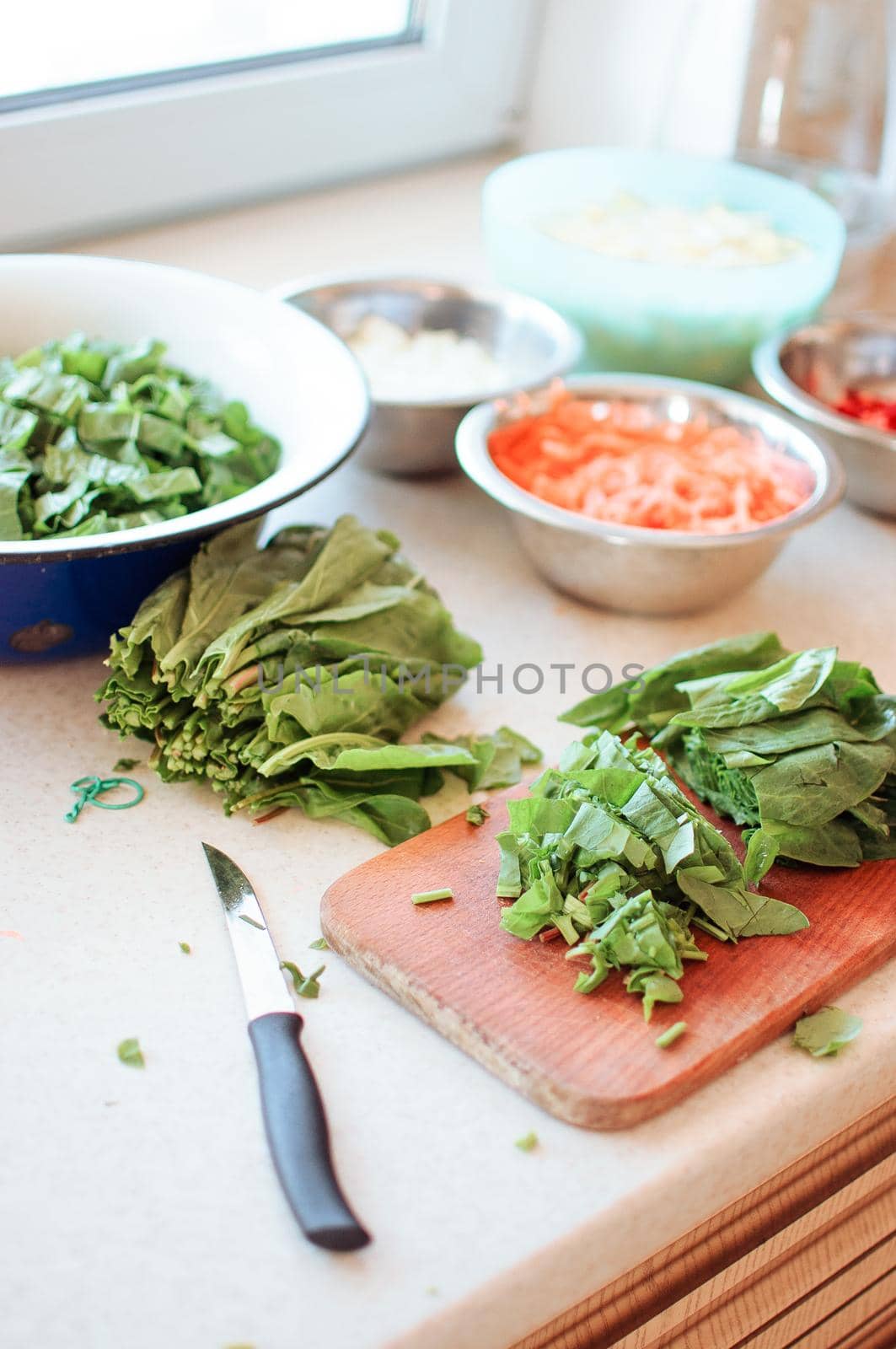 Bright fresh leaves of sorrel on a cutting board. Rustic style, against the background of vegetables in bowls: carrots, onions, pepper chopped.Copy space. by Alla_Morozova93