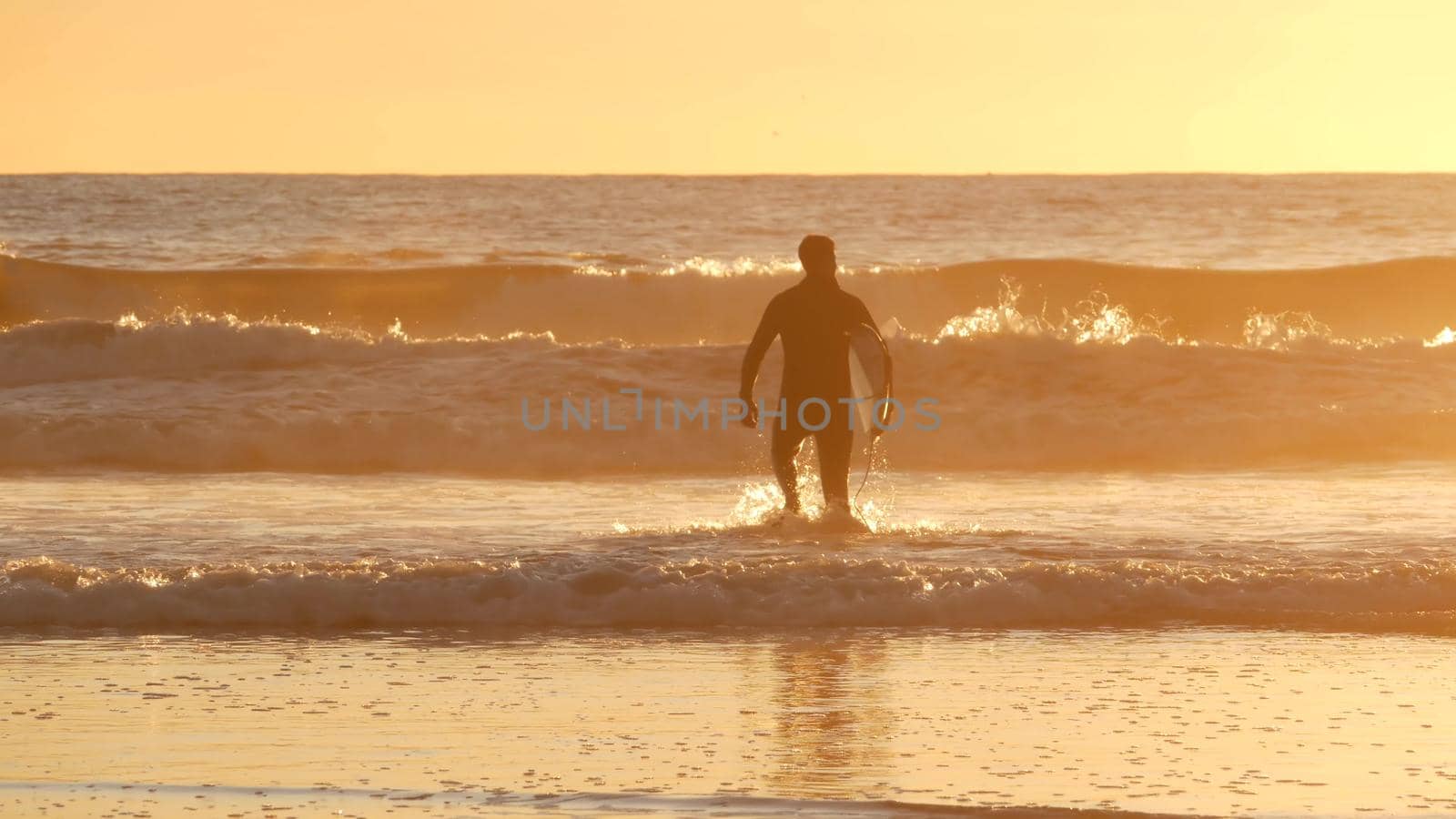 Surfer silhouette, pacific ocean beach sunset. People enjoy surfing. Oceanside, California USA by DogoraSun