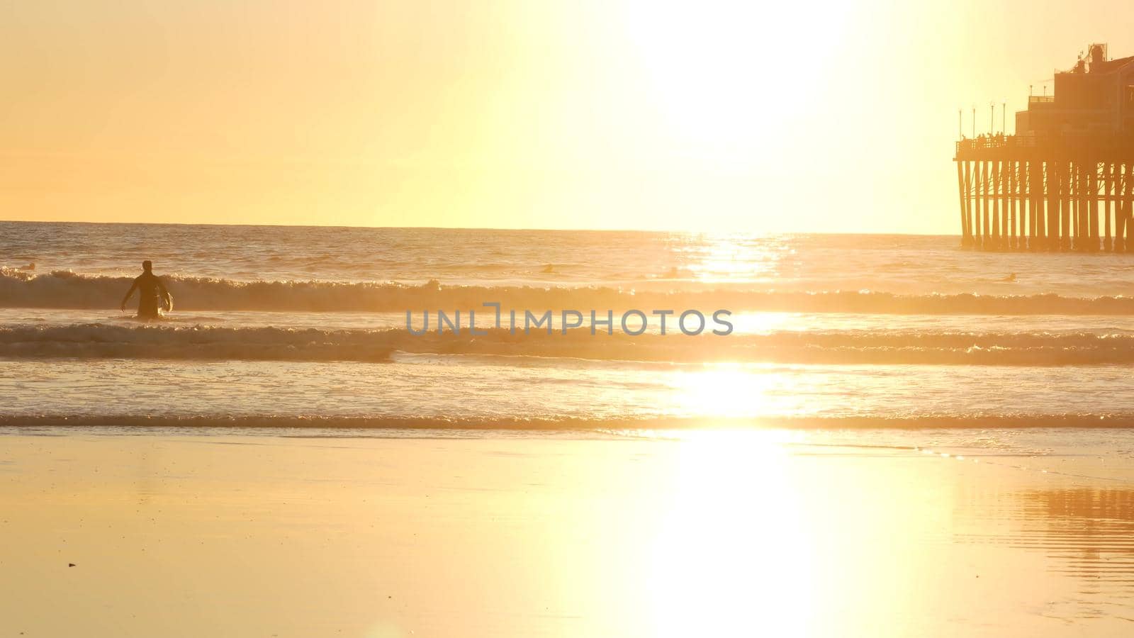 Surfer silhouette, pacific ocean beach sunset. People enjoy surfing. Oceanside, California USA by DogoraSun