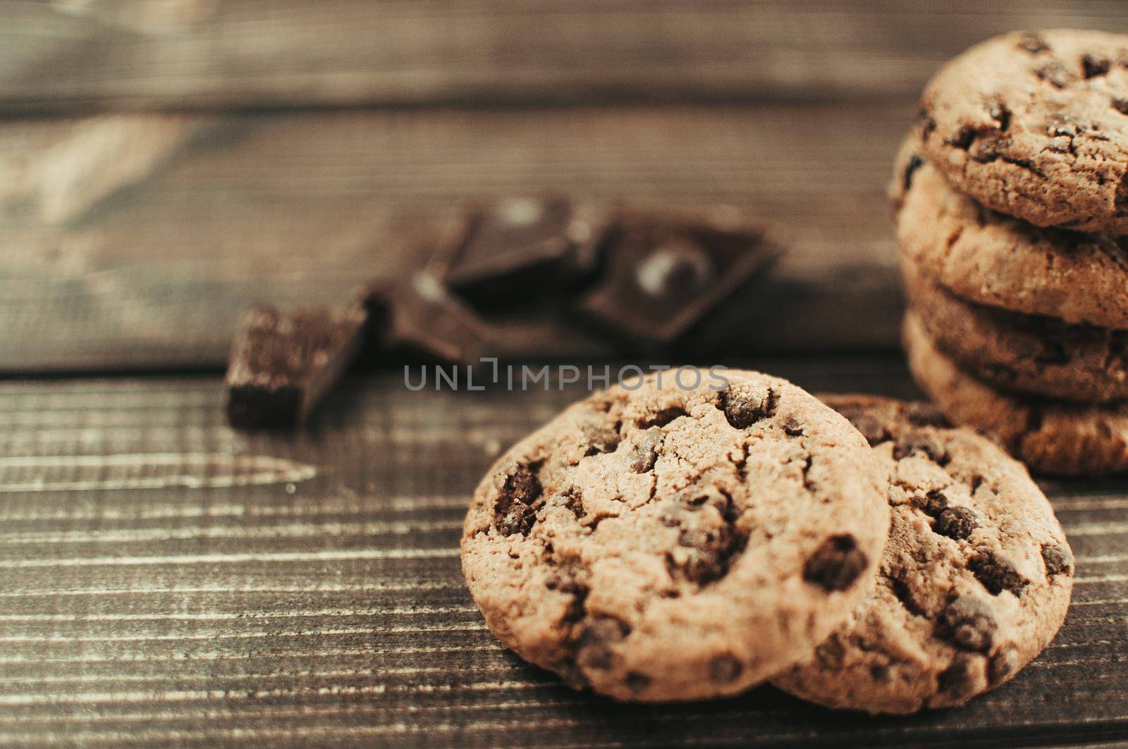 A stack of oatmeal cookies with chocolate pieces is lying on a wooden table. Rustic table. Vintage toning. Dietary useful cookies without gluten. Copy space.