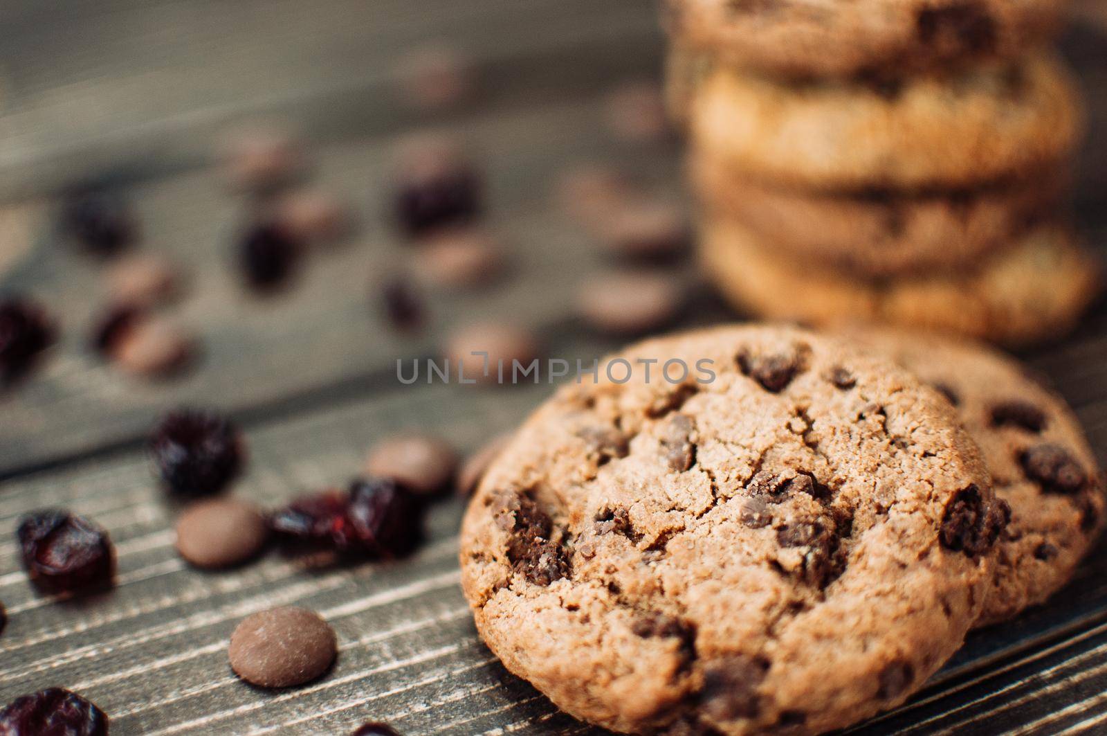 A stack of oatmeal cookies with chocolate pieces and candied fruits lies on a wooden table. Rustic table. Vintage toning. Dietary useful cookies without gluten. Copy space.