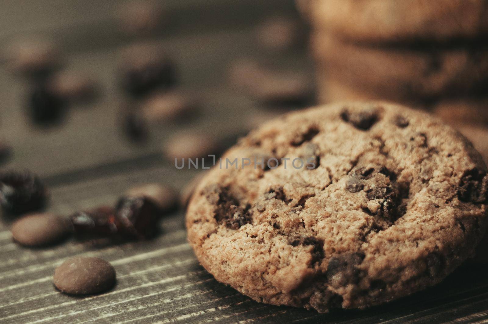 A stack of oatmeal cookies with chocolate pieces and candied fruits lies on a wooden table. Rustic table. Vintage toning. Dietary useful cookies without gluten. Copy space.