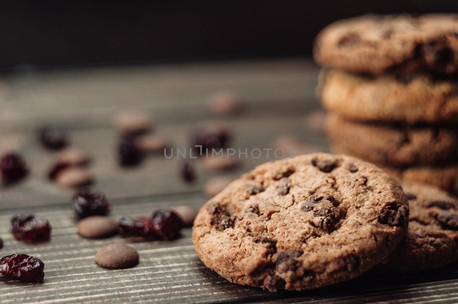 A stack of oatmeal cookies with chocolate pieces and candied fruits lies on a wooden table. Rustic table. Vintage toning. Dietary useful cookies without gluten. Copy space.