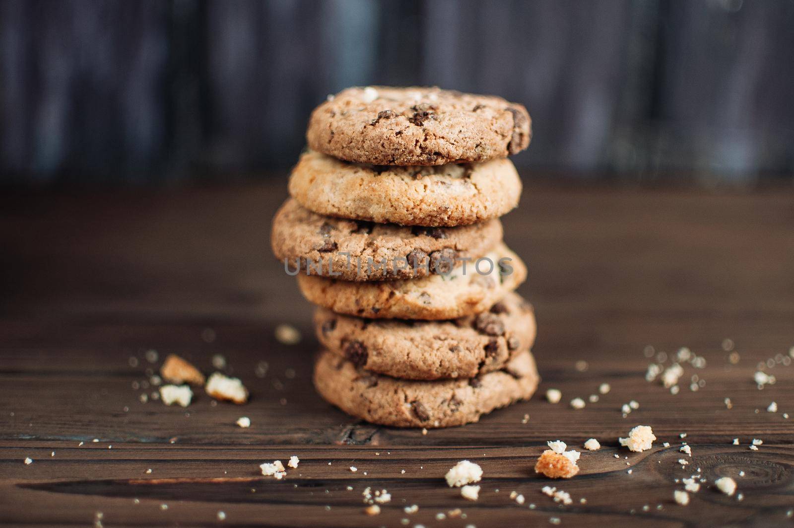 Cookies with chocolate worth a stack on a wooden table in a rustic style. Crumbs from biscuits on wooden boards. Selective focus