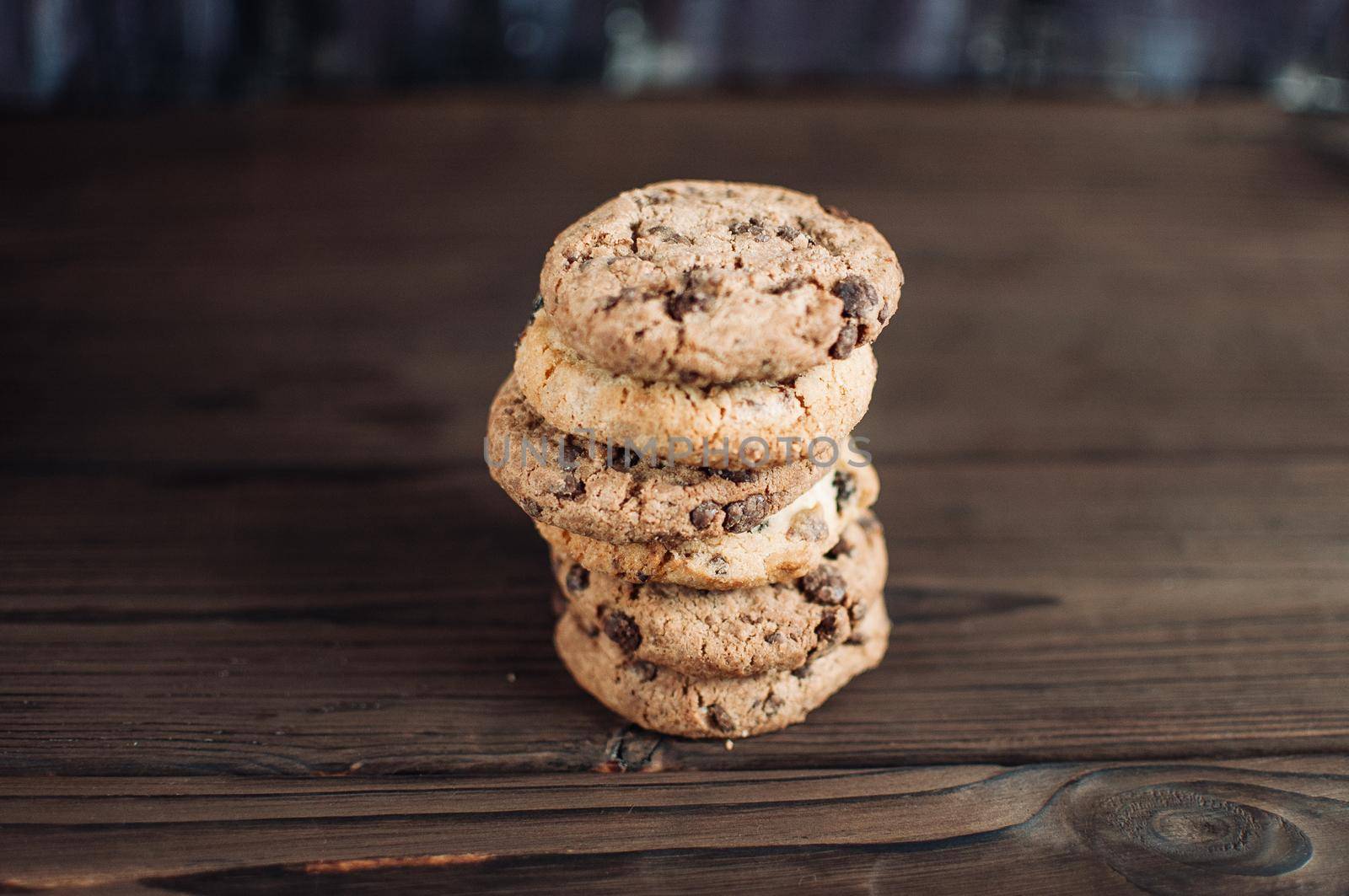 A stack of chocolate chip cookies lies on a wooden table. Rustic table. Vintage toning. Dietary useful cookies without gluten. Copy space.