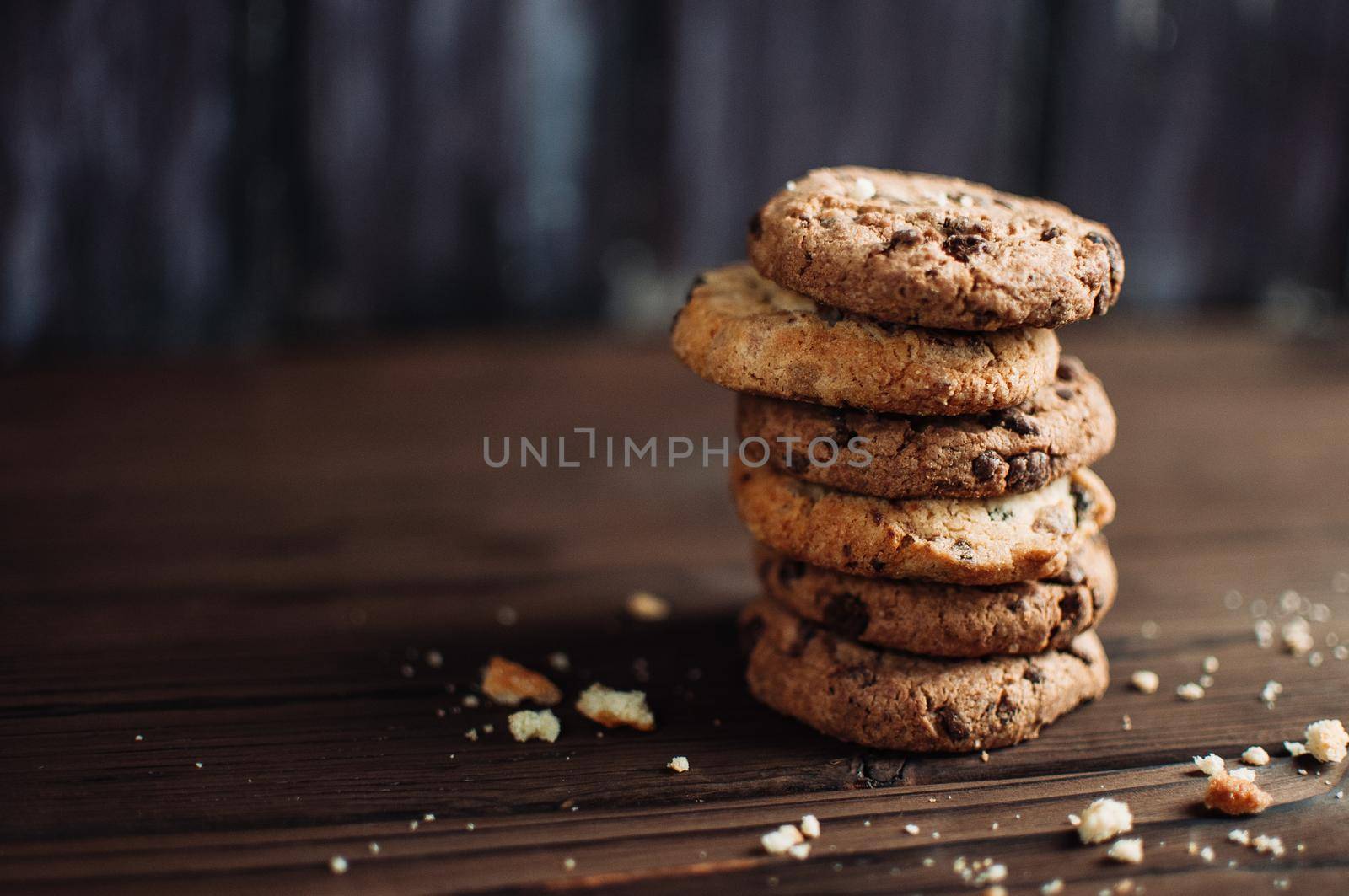 Cookies with chocolate worth a stack on a wooden table in a rustic style. Crumbs from biscuits on wooden boards. Selective focus