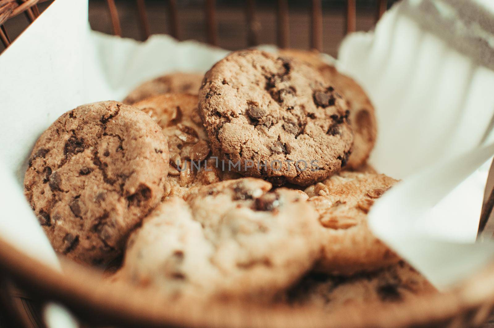 Cookies with chocolate lies in a wicker basket. A basket with gluten free cookies on a wooden table. Selective focus.