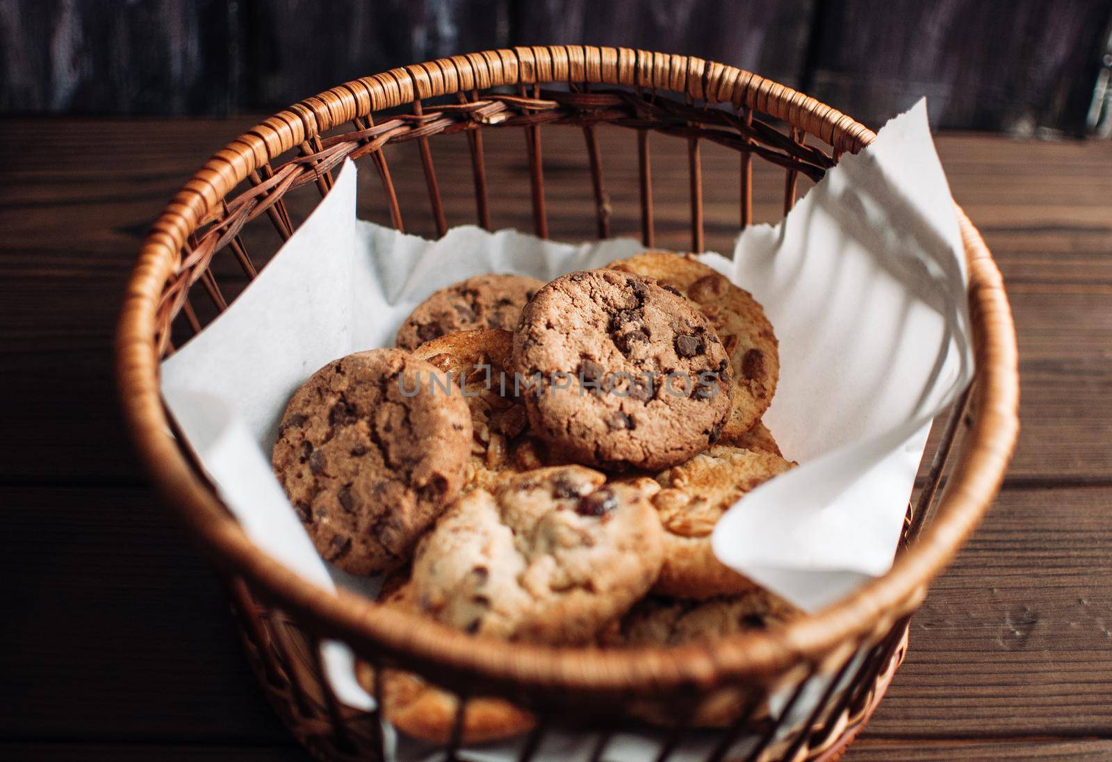 Cookies with chocolate lies in a wicker basket. A basket with gluten free cookies on a wooden table. Selective focus.