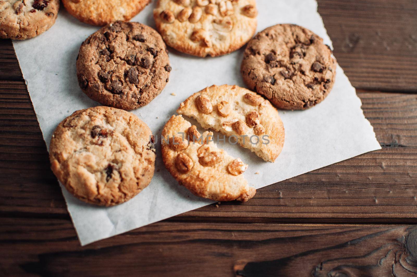 Chocolate cookies on parchment paper. Broken biscuits on a wooden table. Selective focus.