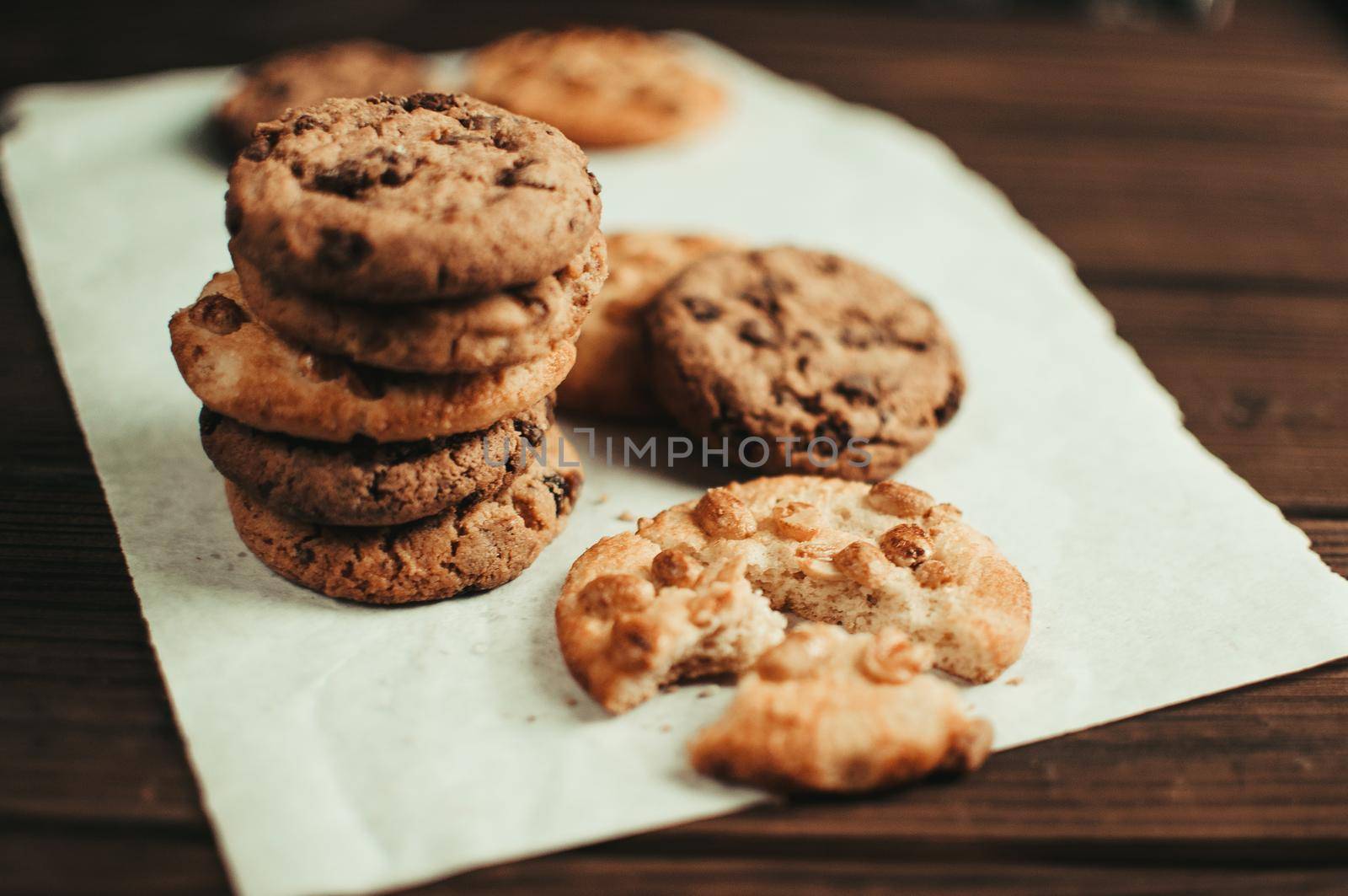 Chocolate cookies on parchment paper. Broken biscuits on a wooden table. Selective focus.