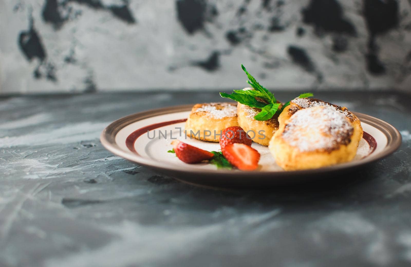 Gourmet breakfast - curd pancakes, cheesecakes, curd pancakes with strawberries, mint and icing sugar in a white plate. Selective focus