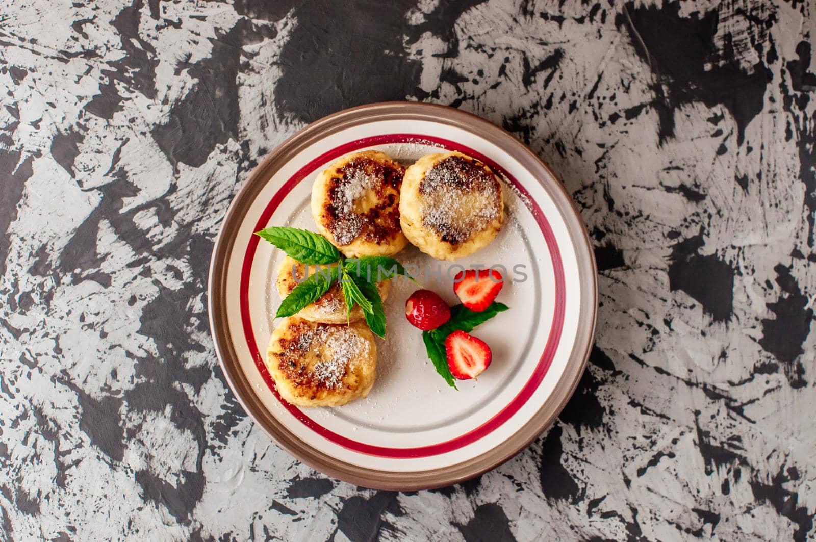 Gourmet breakfast - curd pancakes, cheesecakes, curd pancakes with strawberries, mint and icing sugar in a white plate. Selective focus. Top view.